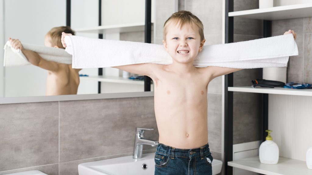 Angry shirtless boy holding towel hand clenching his teeth camera bathroom