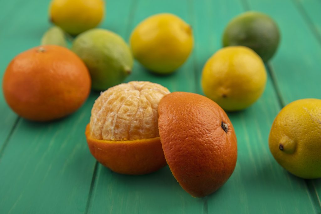 Front view orange with peeled peels on green background