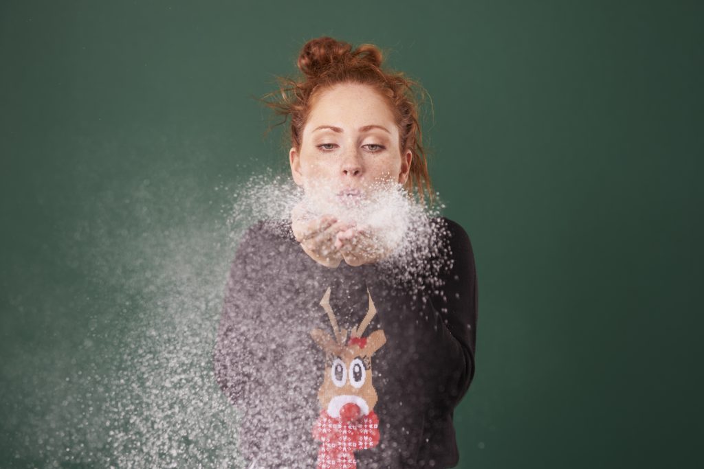 Young woman blowing fake snow
