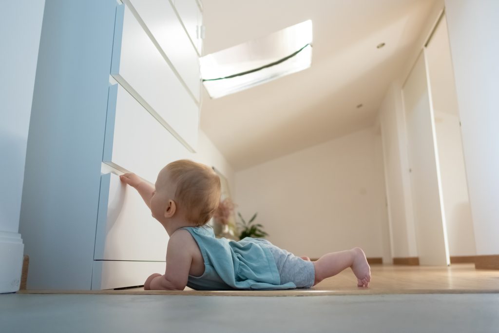 Adorable newborn opening closed wardrobe and lying on belly