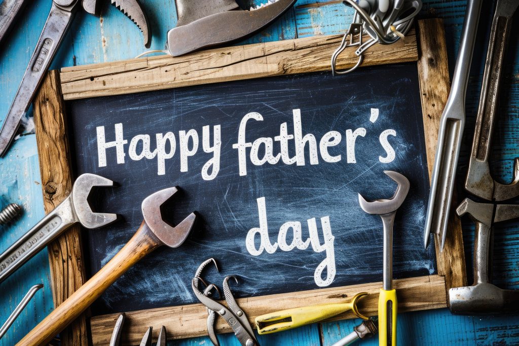 Phrase "happy father's day" written on a blackboard with wooden frame, with old work tools
