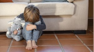 Little boy outdoors upset holding his toy